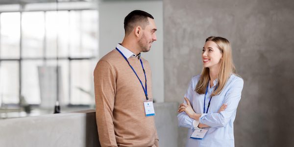 business, people and corporate concept - happy smiling man and woman with conference badges at office